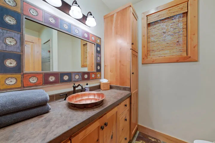Wood-finish cabinetry and storage tower with dark hardware