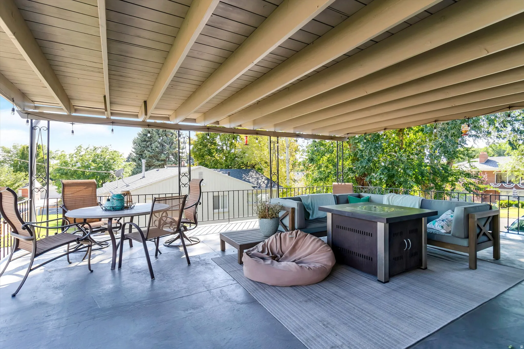 Expansive covered patio featuring a slatted ceiling, dark gray concrete flooring, and wrought iron railings