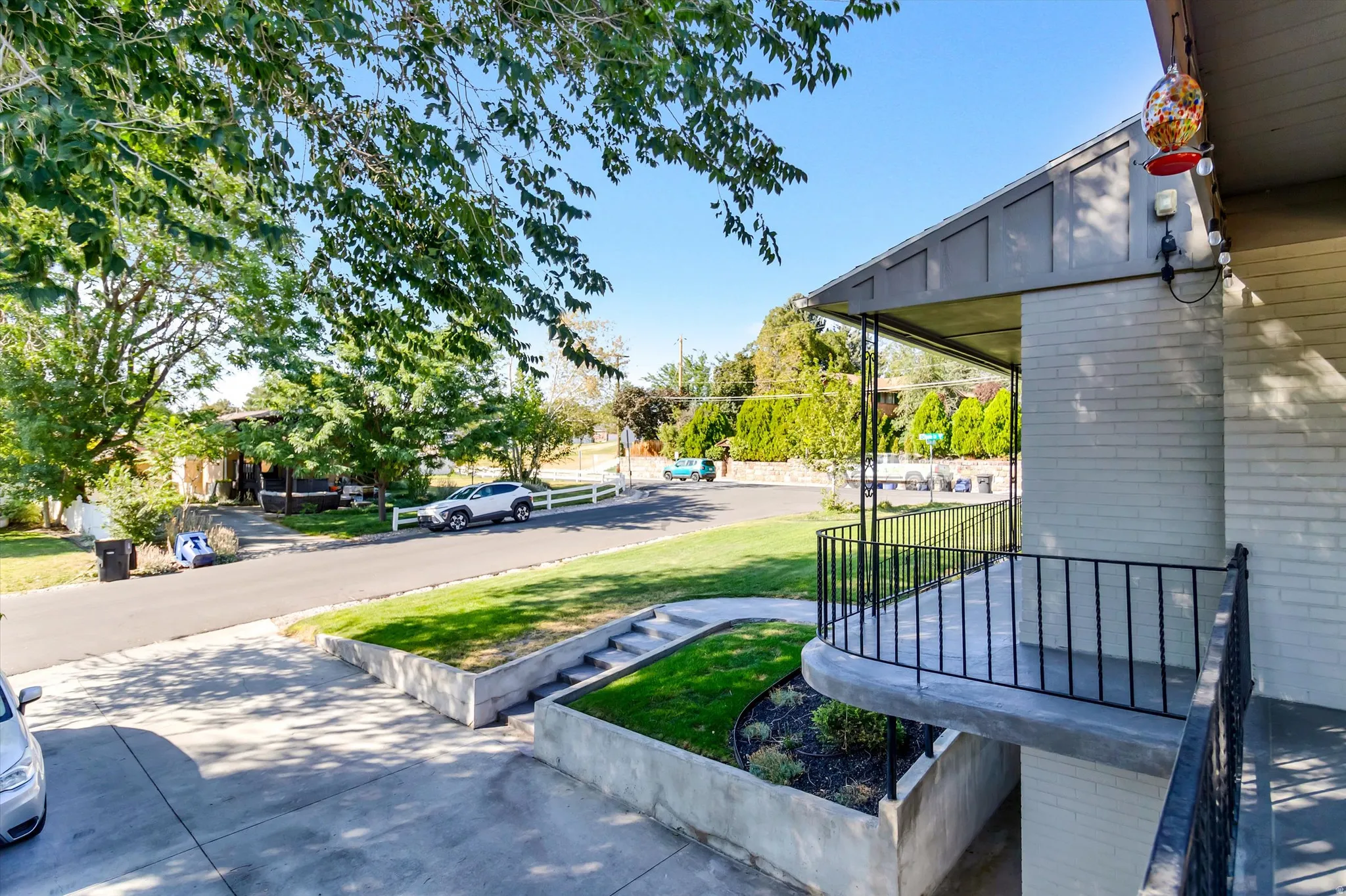 Covered front porch with black metal railing, painted brick facade.