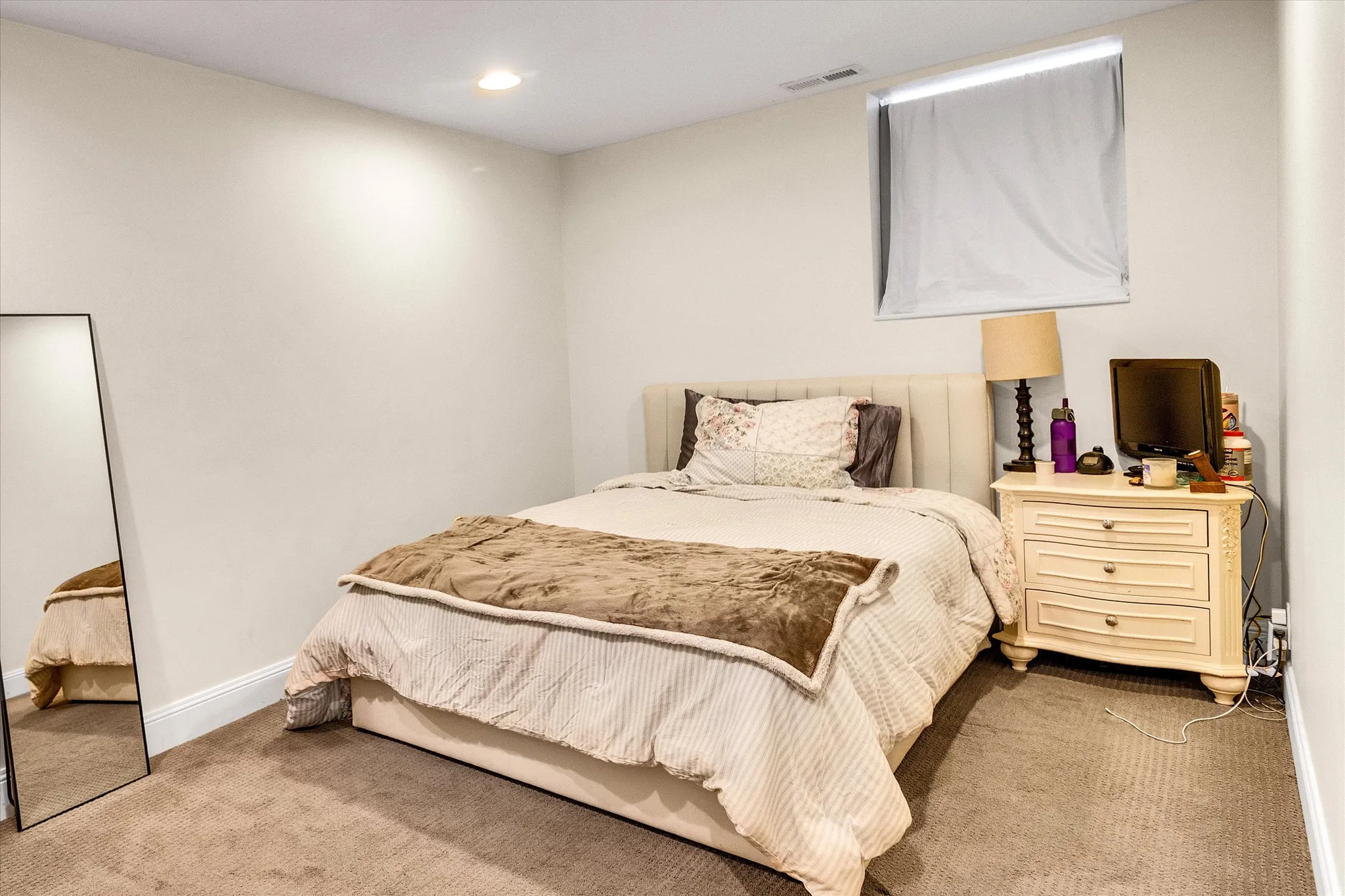 Carpeted room featuring light-toned walls, a recessed ceiling light, and a window with a roller shade