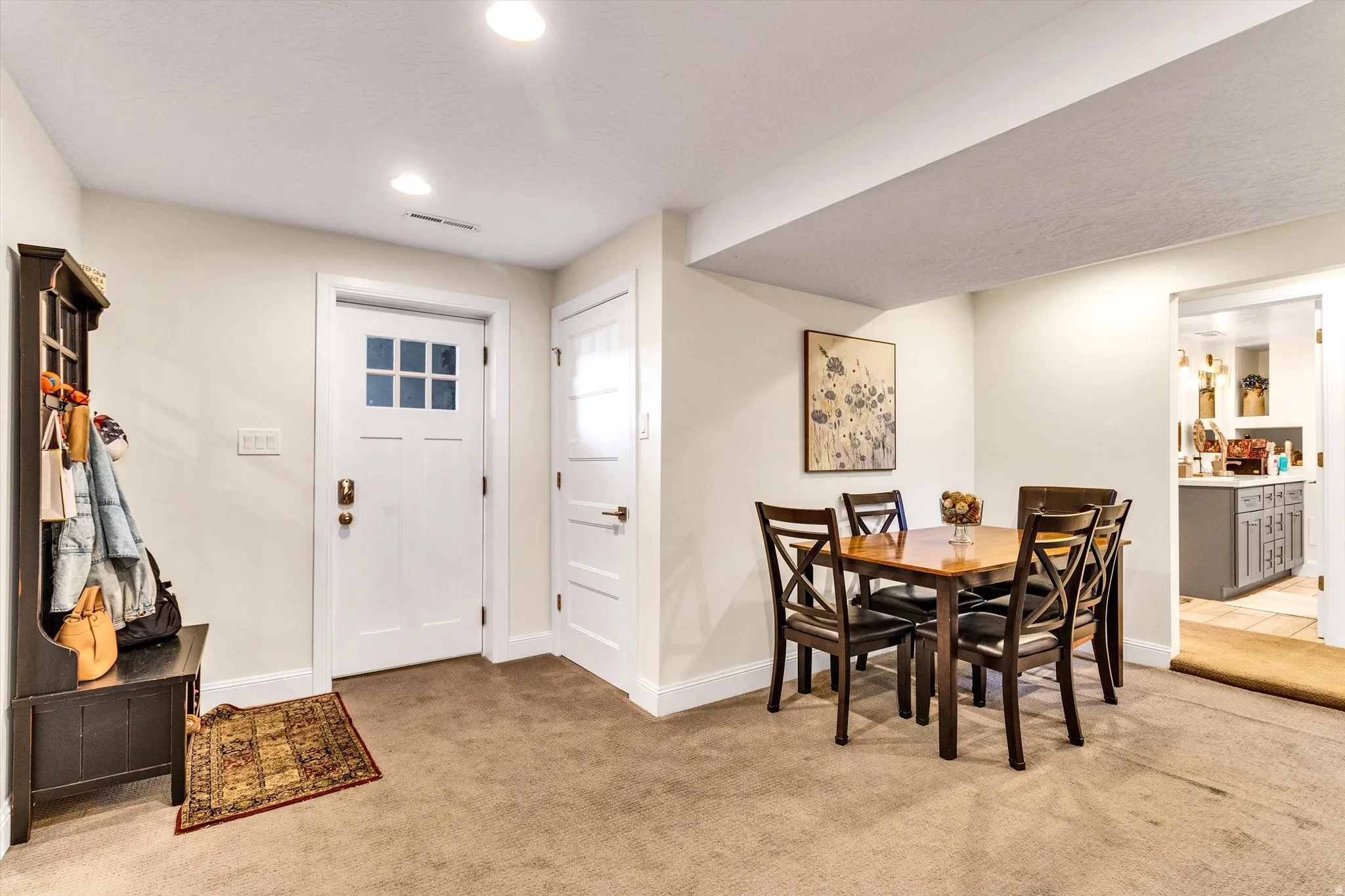 Carpeted entry area featuring a white craftsman-style door with clear glass panes and an adjacent paneled door