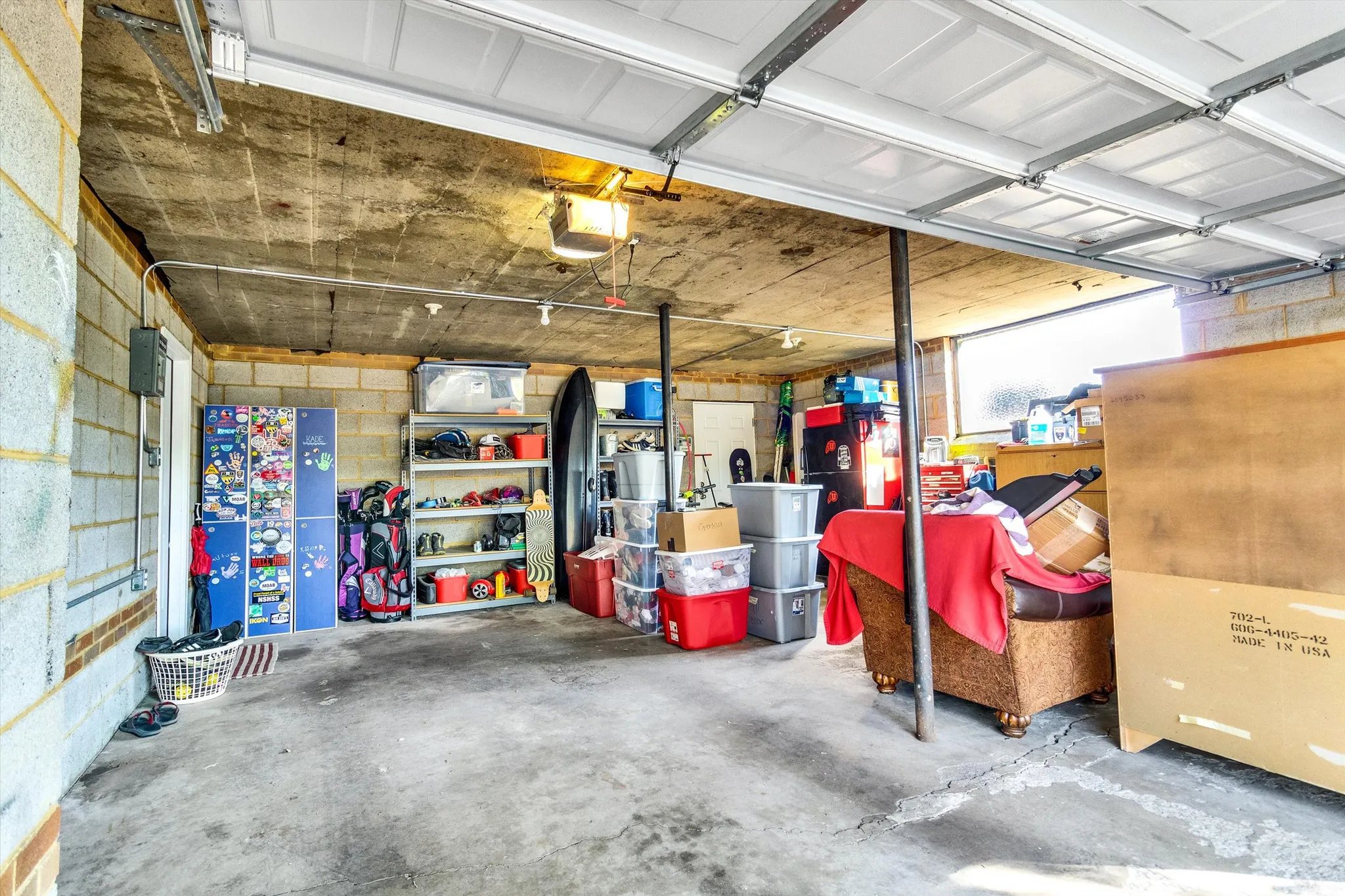 Spacious garage featuring a concrete floor, concrete block walls, overhead lighting, and an automatic garage door