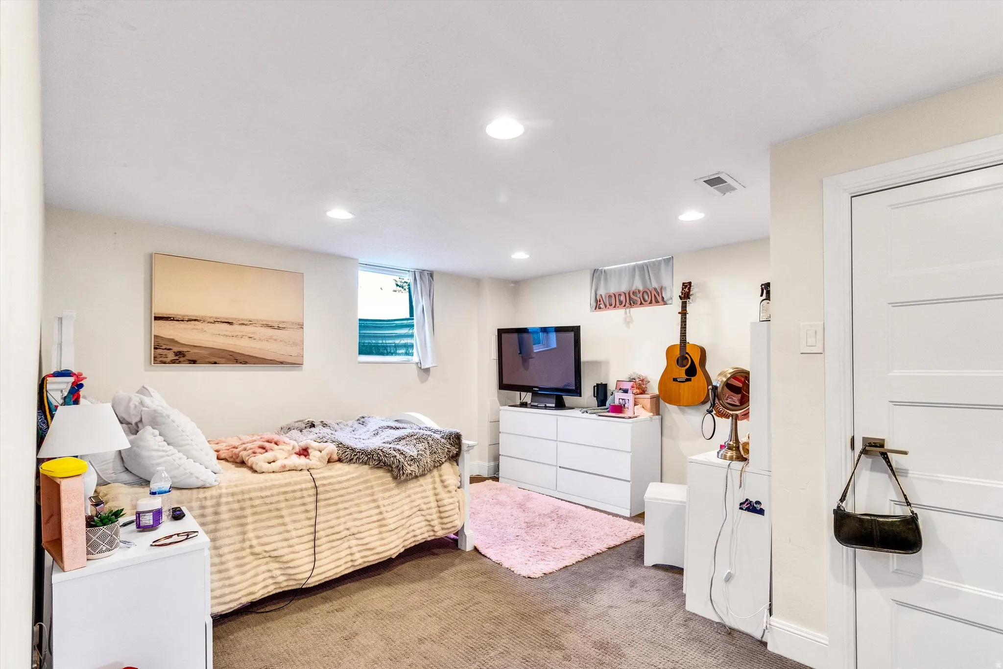 Recessed lighting illuminates this room featuring light-toned walls and a window with natural light