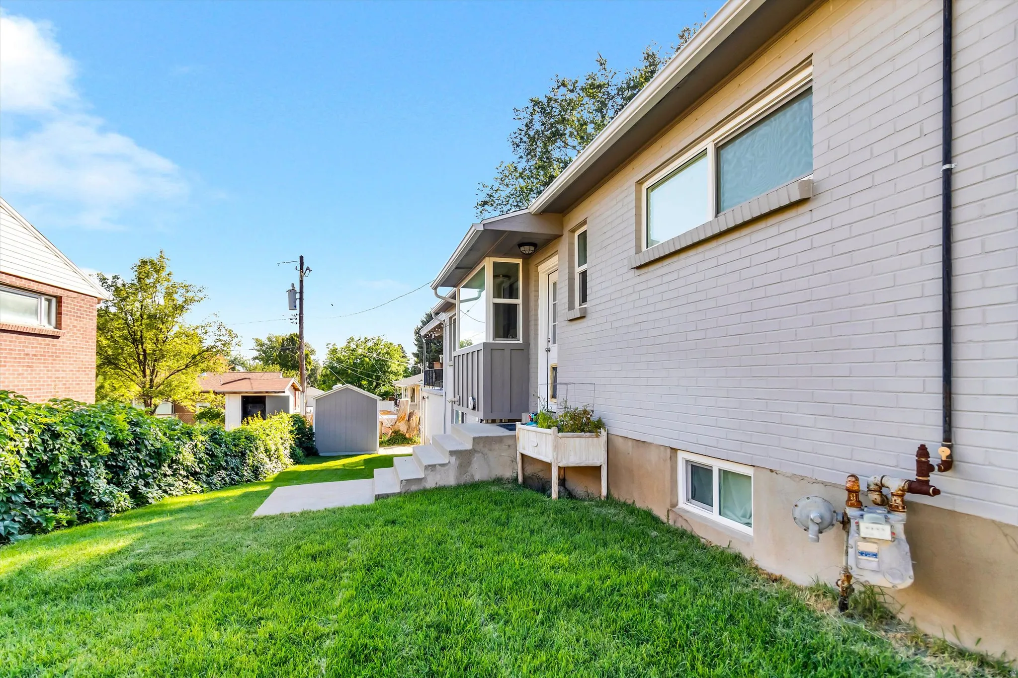 Manicured lawn with a brick exterior featuring a painted finish and a concrete patio