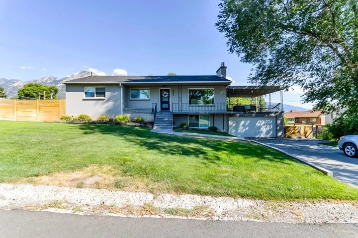 Rambler residence, corner lot. Large covered patio with metal railings provides a spacious outdoor living area.