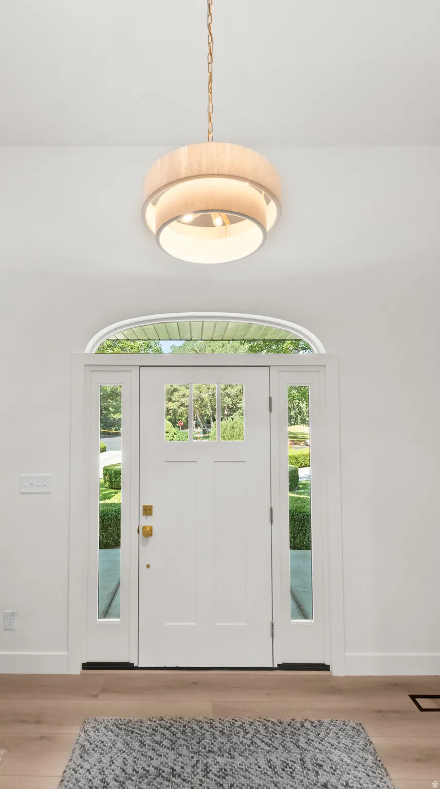 Entryway featuring a white paneled door with glass inserts, transom window, and brass hardware