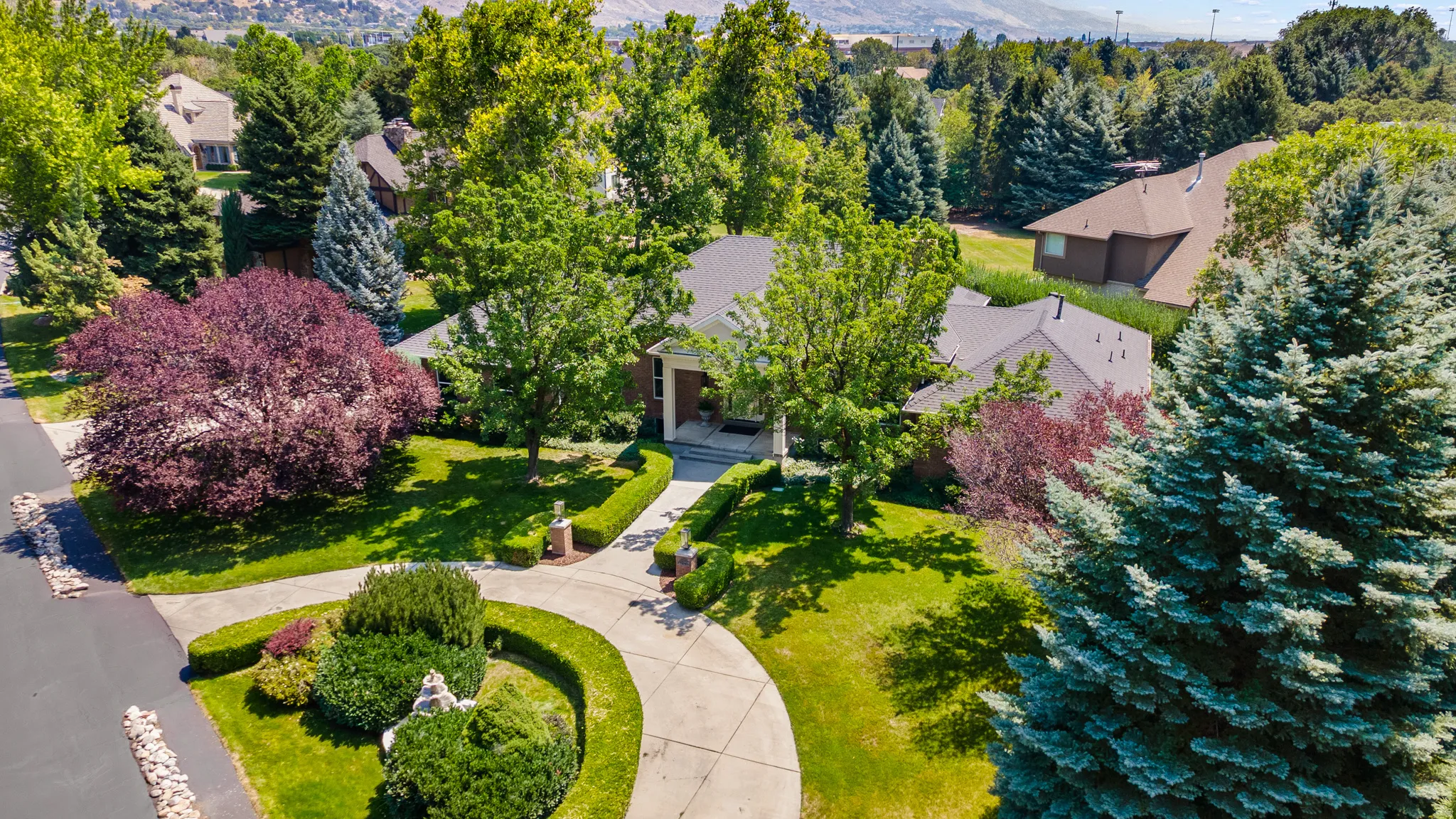 Circular driveway with decorative landscaping, mature trees, and a well-maintained lawn