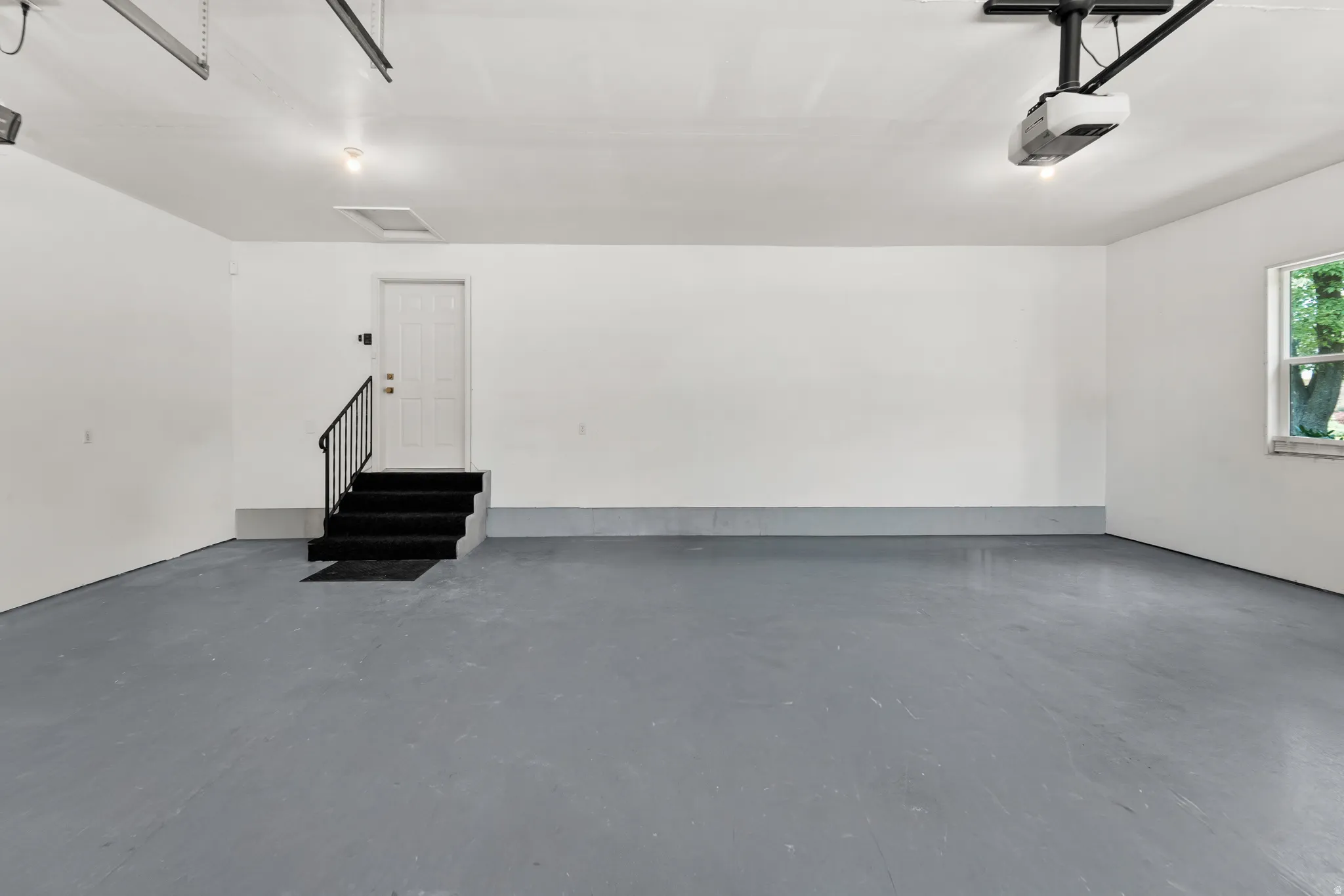 Spacious garage with painted concrete flooring, white walls, and a window for natural light