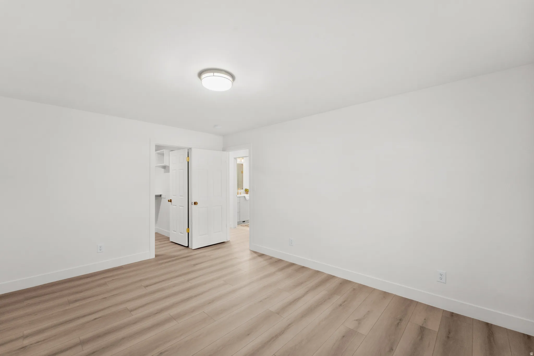 Wood-finish flooring, white walls, flush mount lighting, and a built-in closet with shelving