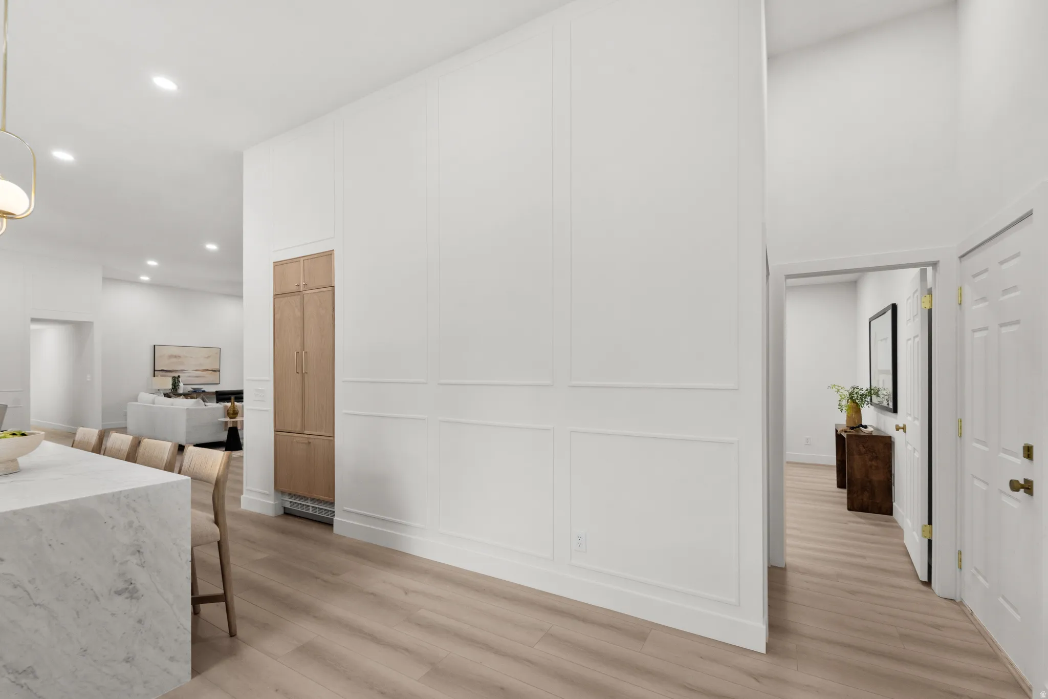 Open-concept design with wood-finish flooring, recessed lighting, and a white paneled wall accent