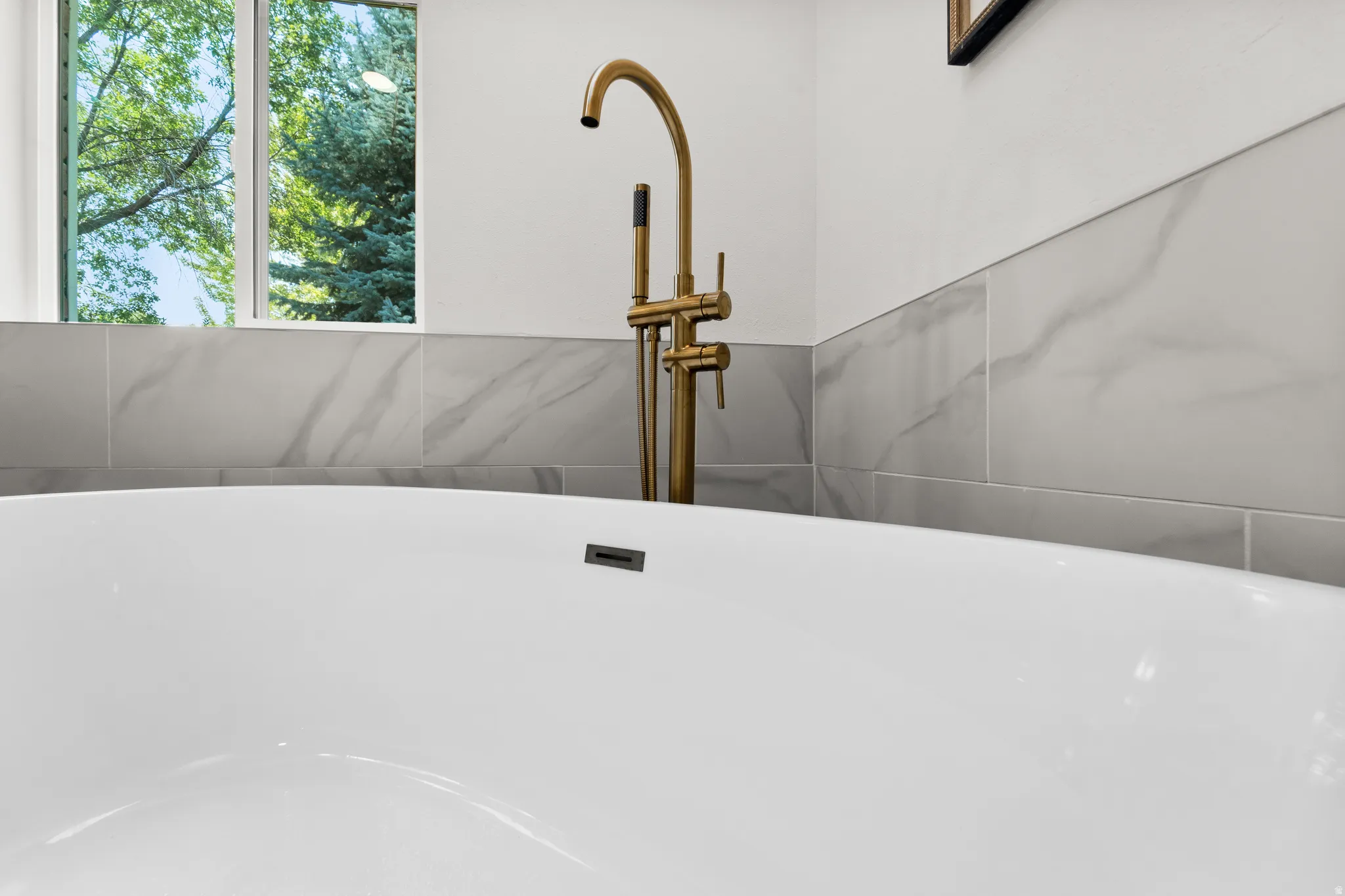 Luxurious freestanding soaking tub with polished brass floor-mounted faucet and hand shower
