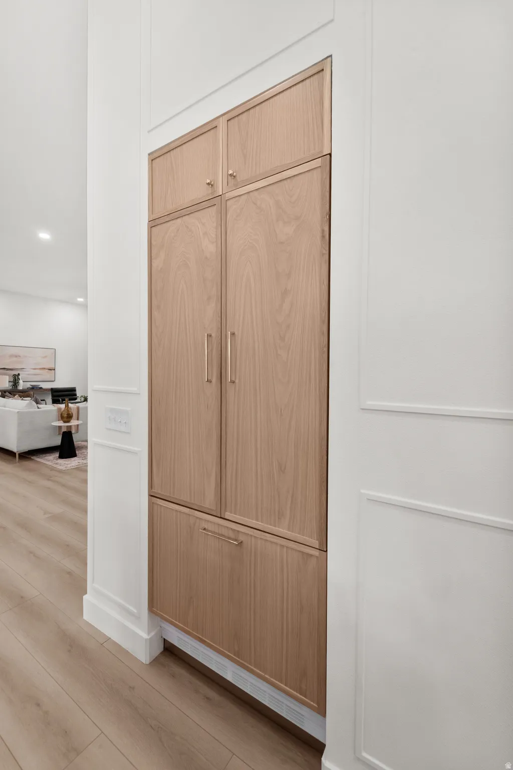 Custom wood-finish cabinetry with integrated refrigerator and freezer drawers, stainless steel hardware, and seamless white trim detailing