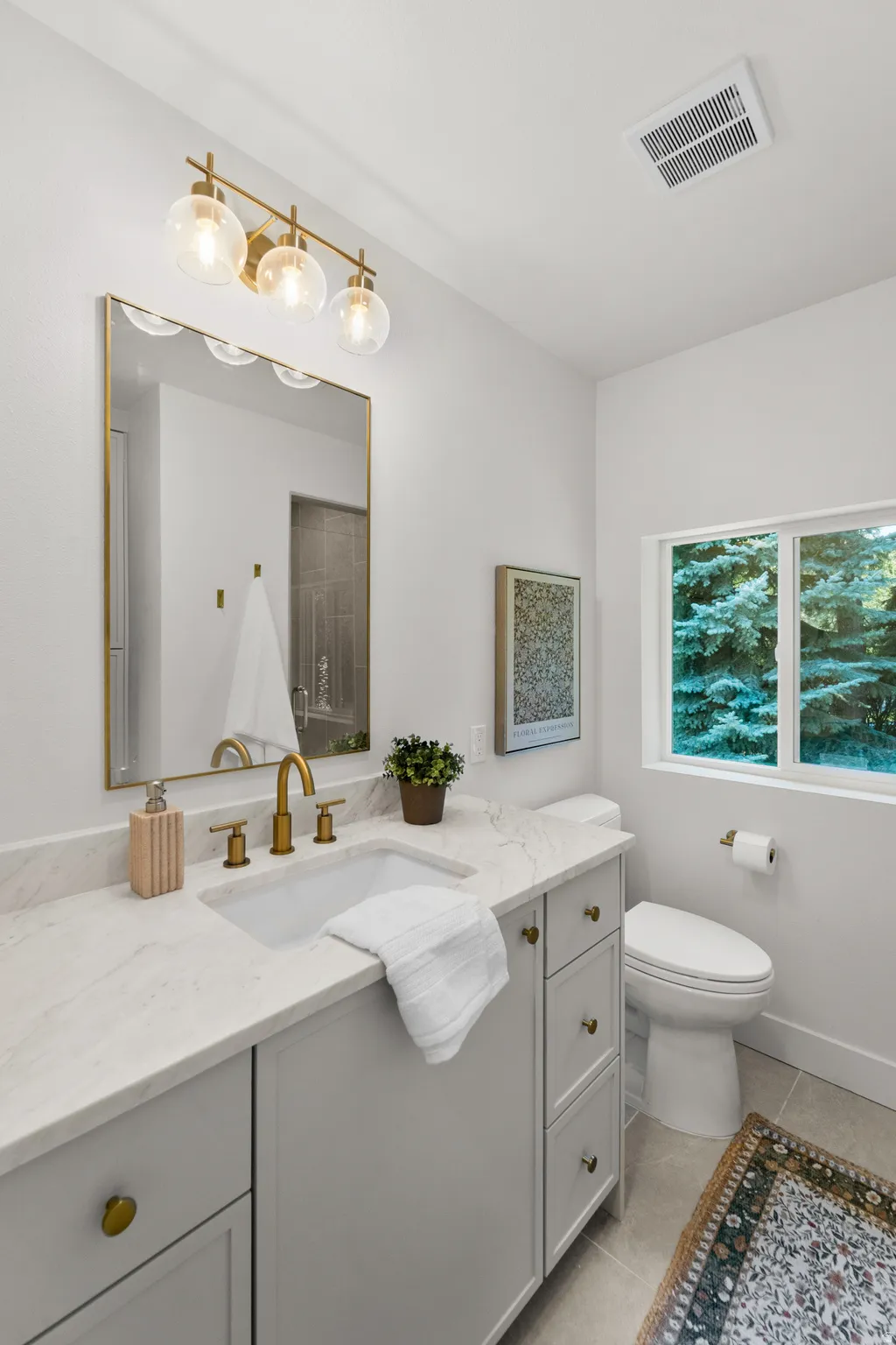 Light gray vanity with a built-in sink, gold-finish faucet, and coordinating hardware
