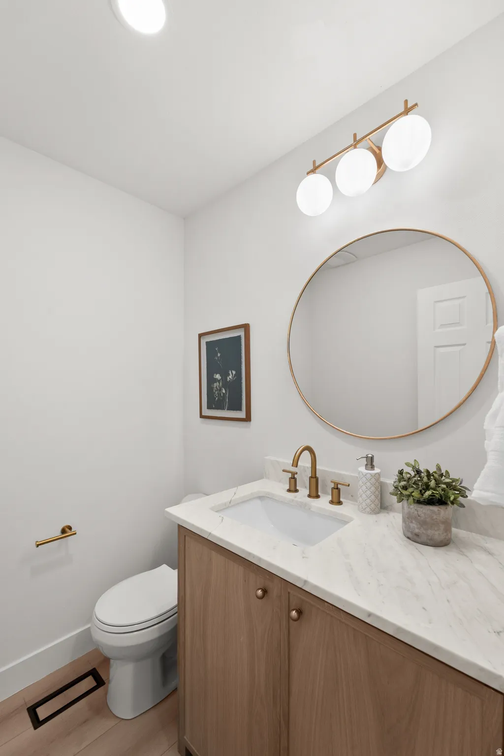 Wood-finish vanity with a built-in sink, stone countertop, and brass-finish fixtures