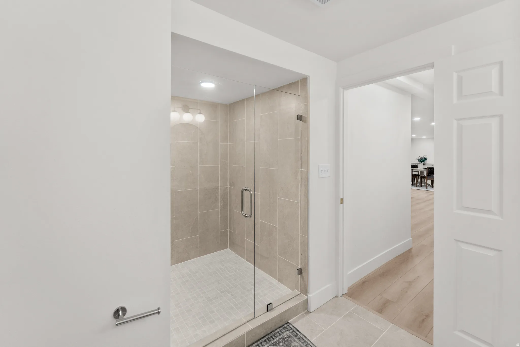 Walk-in shower with clear glass enclosure and light-toned tile surround
