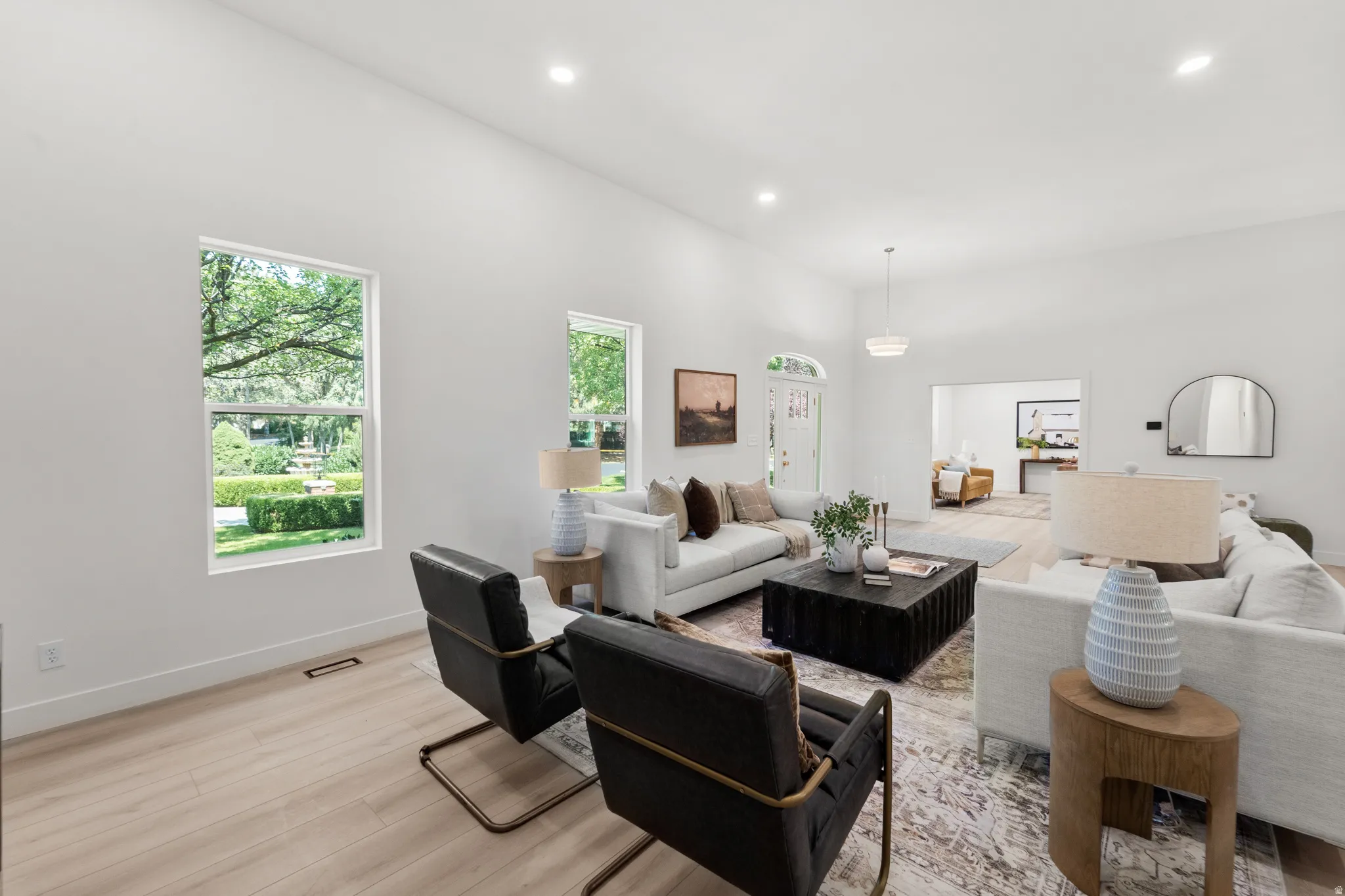 Recessed lighting illuminates the spacious living area with light wood-finish flooring