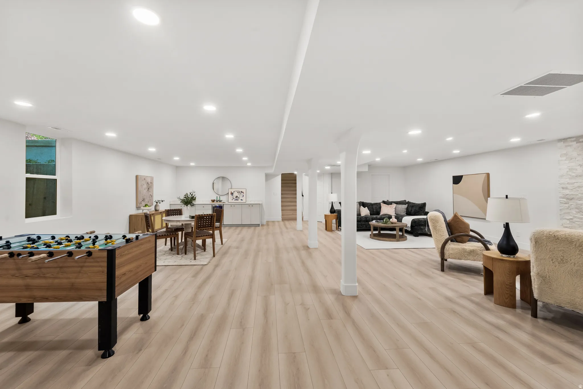 Expansive finished basement with recessed lighting, wood-finish flooring, built-in cabinetry, and a stacked stone accent wall
