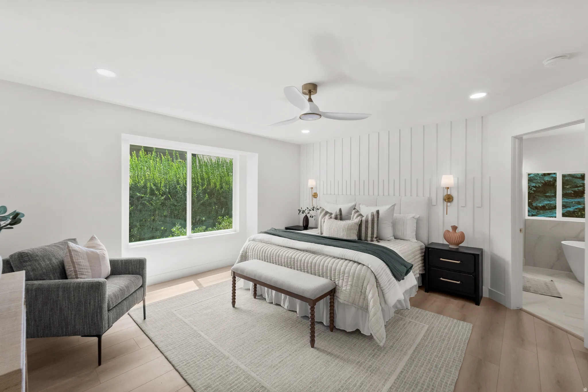 Recessed lighting, wood-finish flooring, ceiling fan, accent wall with vertical paneling, and an open doorway to a bathroom