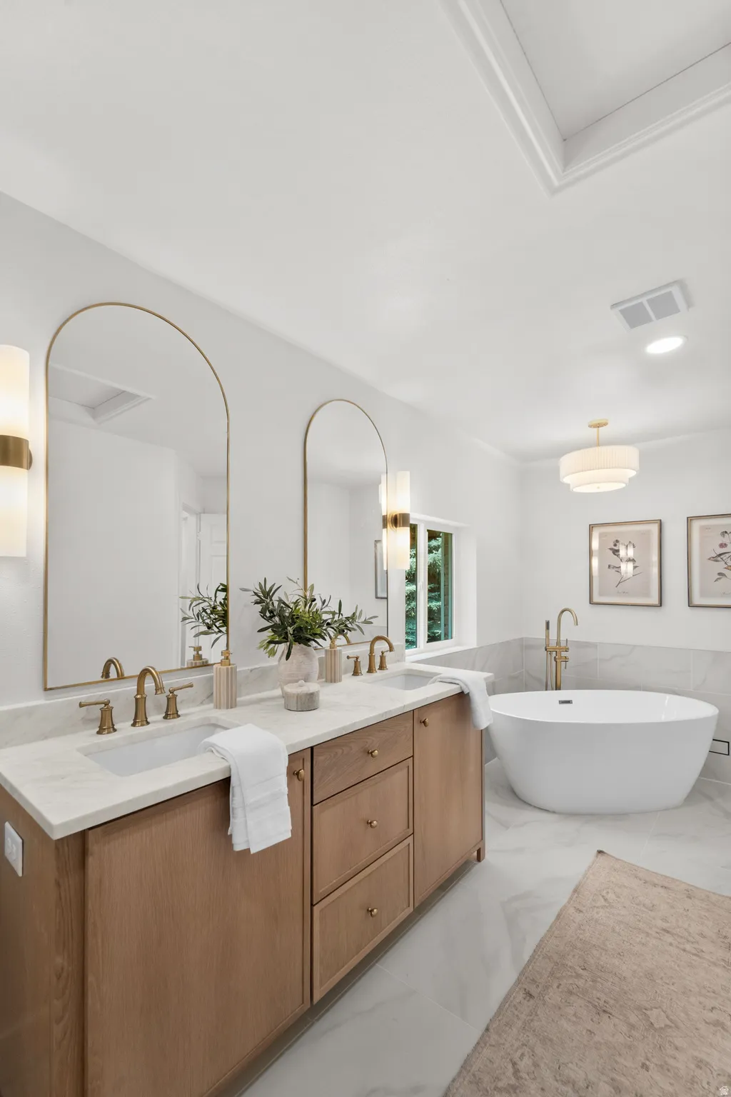 Dual vanity with a light wood finish, white countertop, and arched mirrors
