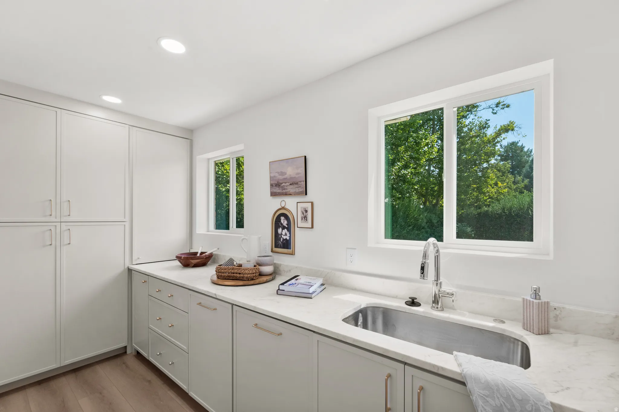 Integrated storage cabinetry, recessed lighting, stone-finish countertops, stainless steel sink, and wood-finish flooring