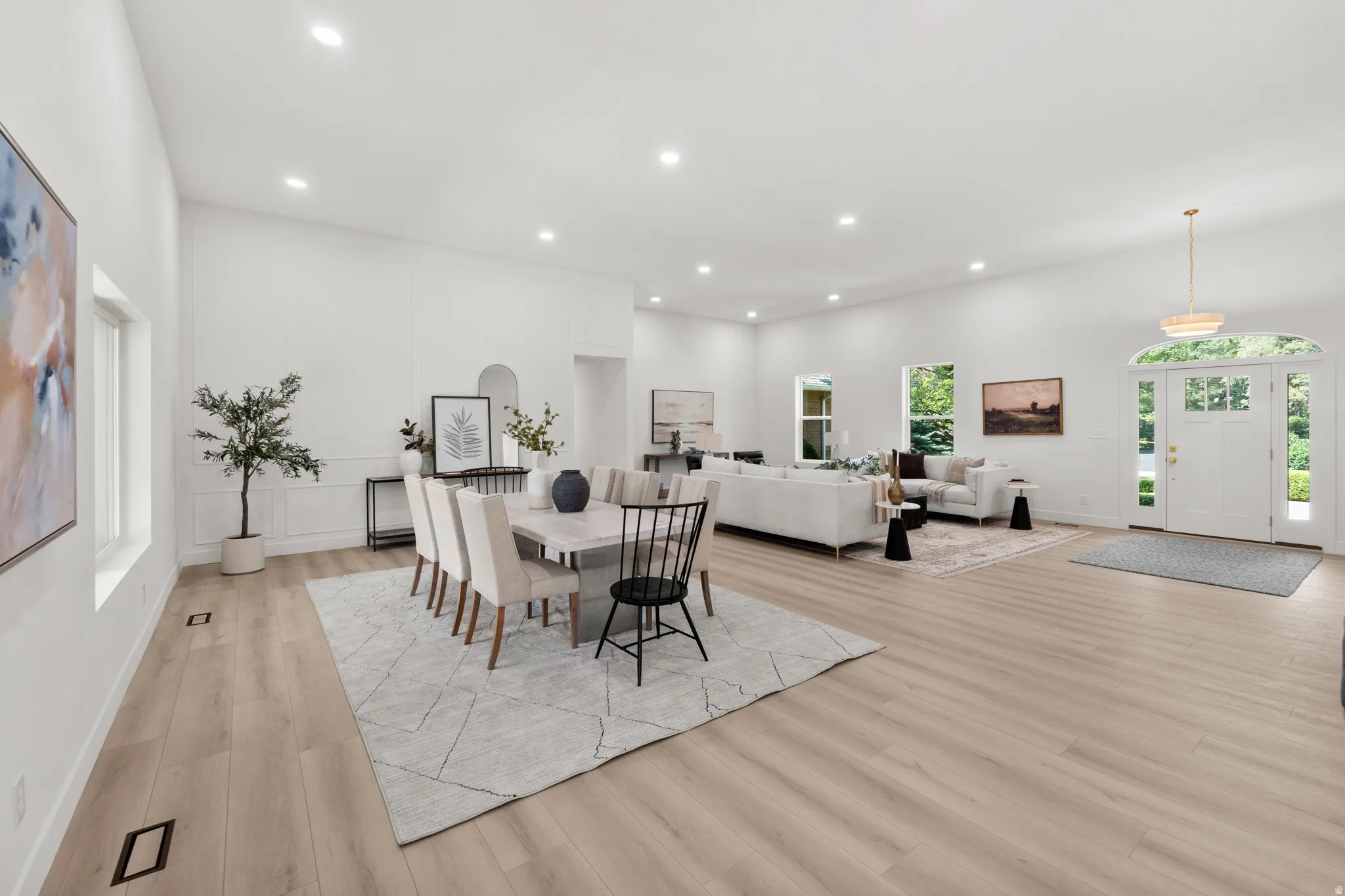 Open concept living area featuring light wood-finish flooring, recessed lighting, and high ceilings