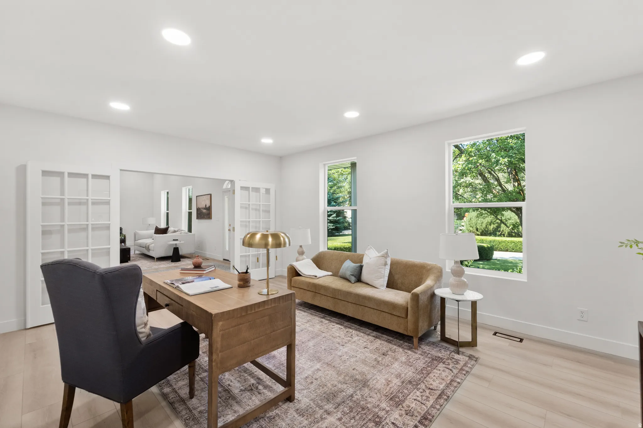 Recessed ceiling lighting, light wood-finish flooring, white walls, and French doors