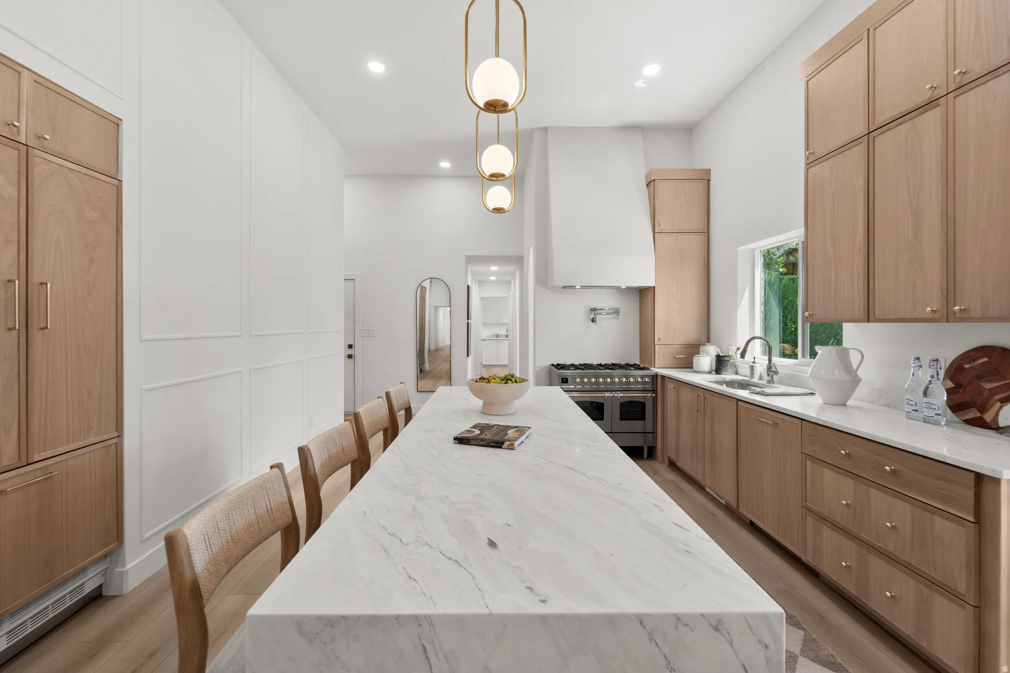 Spacious kitchen featuring a large island with a stone countertop, recessed lighting, wood-finish cabinetry, a stainless steel range, and a built-in refrigerator