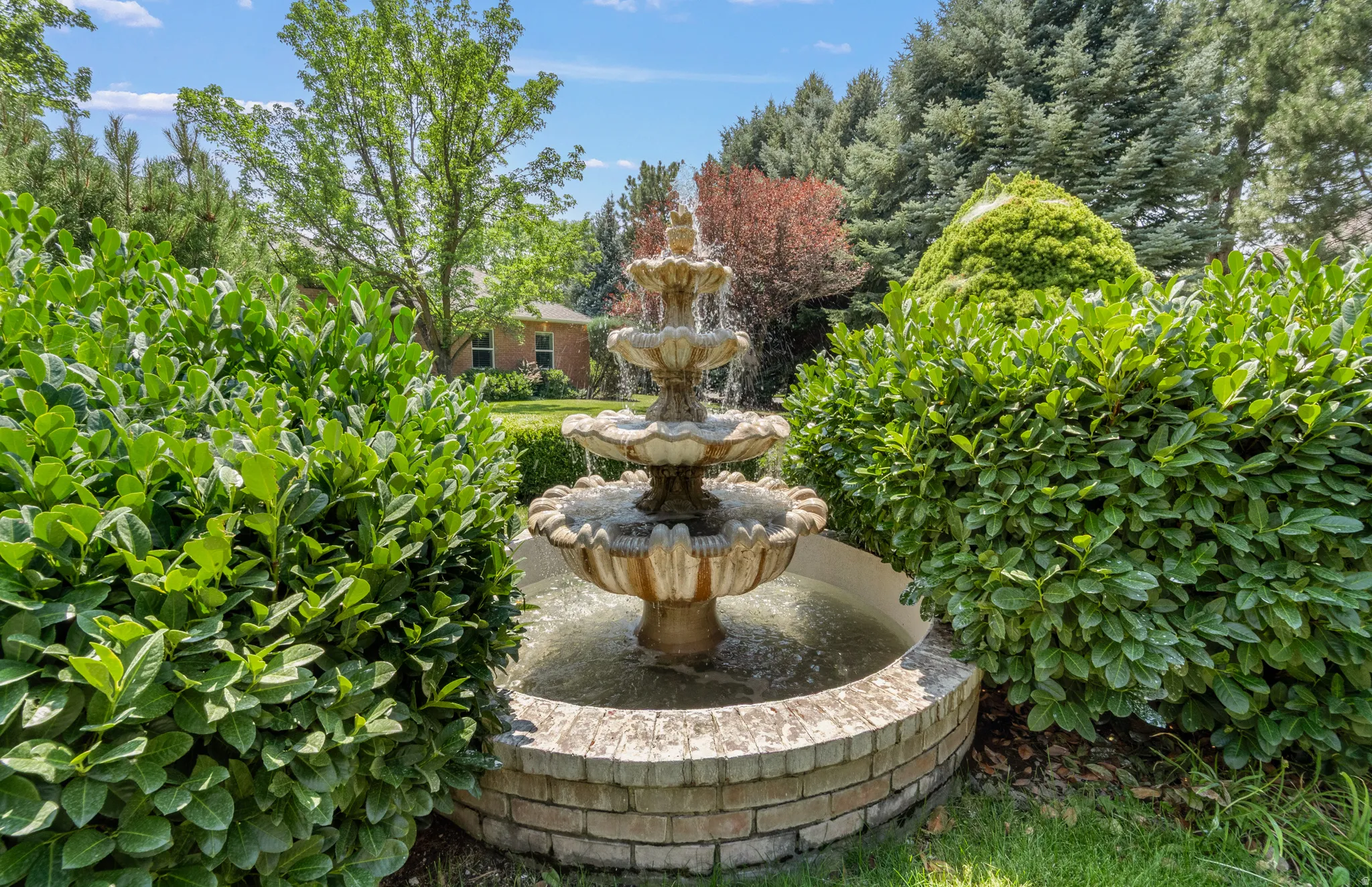 Tiered stone water feature surrounded by established shrubbery and mature trees