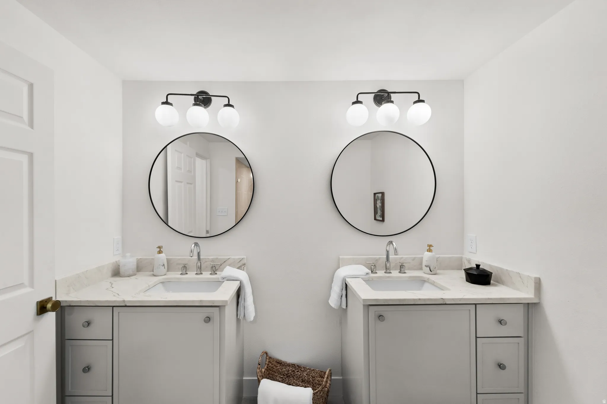 Dual vanity with undermount sinks, stone countertops, and individual round framed mirrors