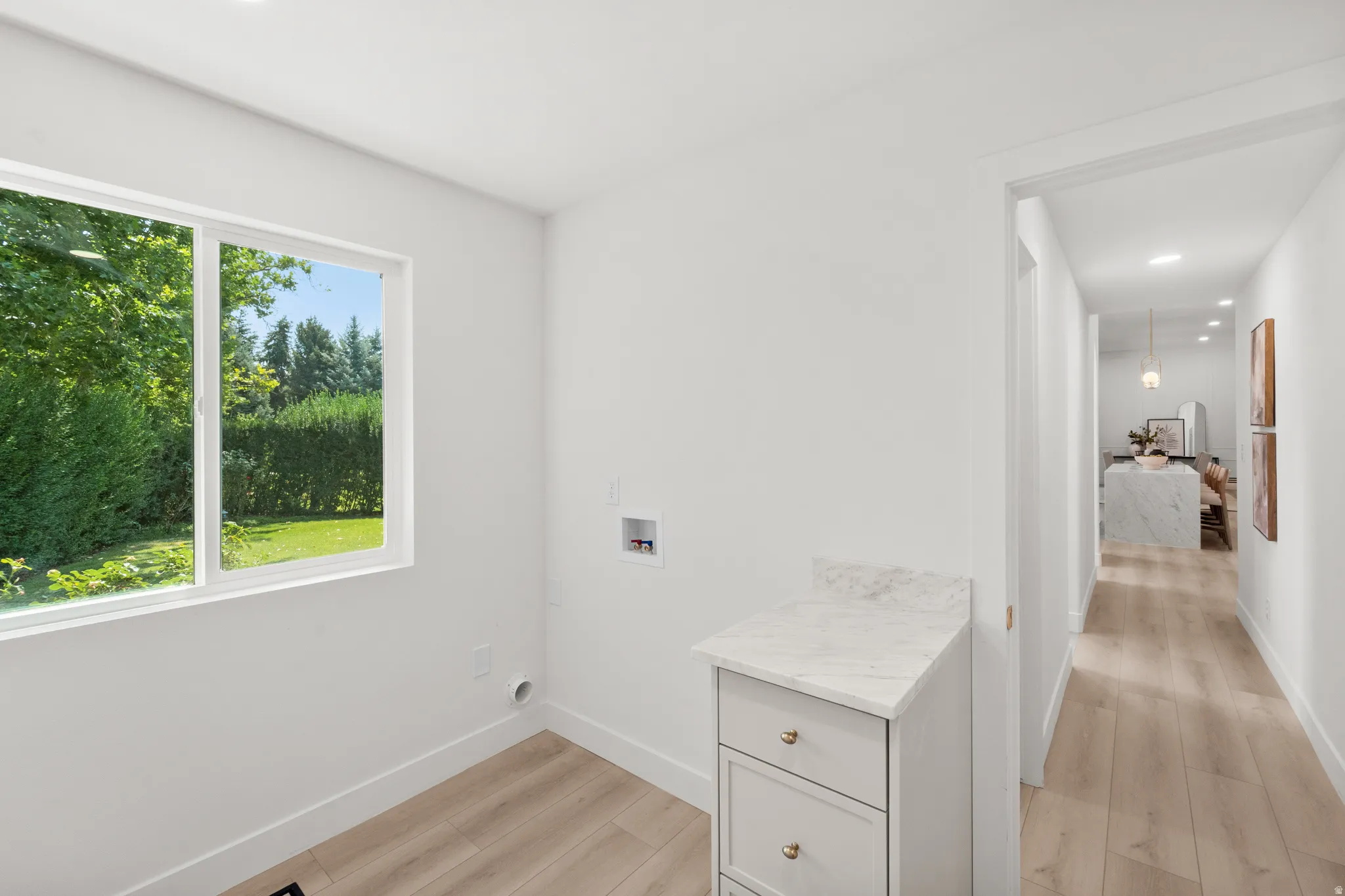 Bright room with a large window, light wood-finish flooring, and a built-in cabinet with a stone countertop