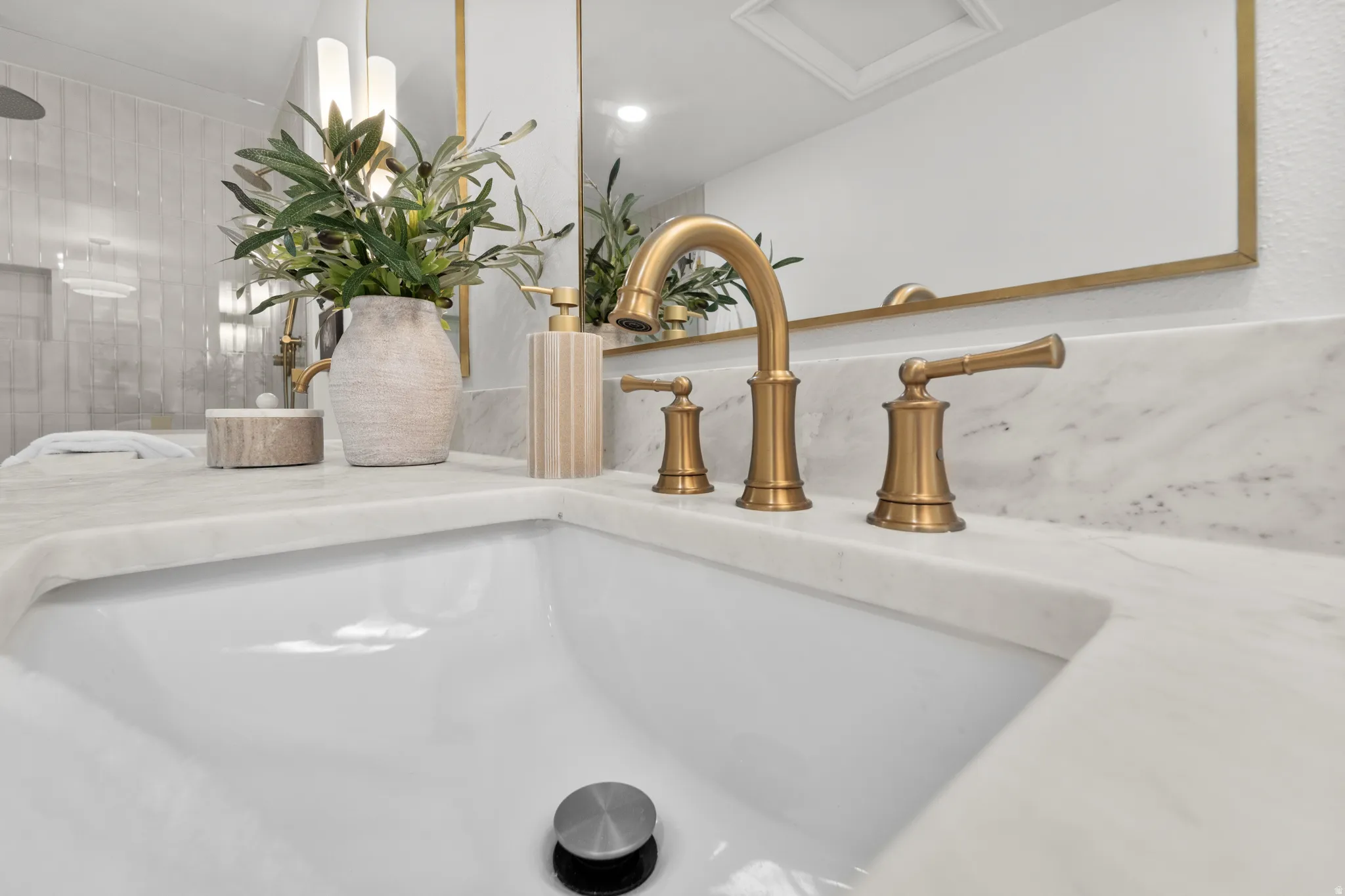 Integrated rectangular sink with a brass-finish faucet, set within a white countertop with subtle veining