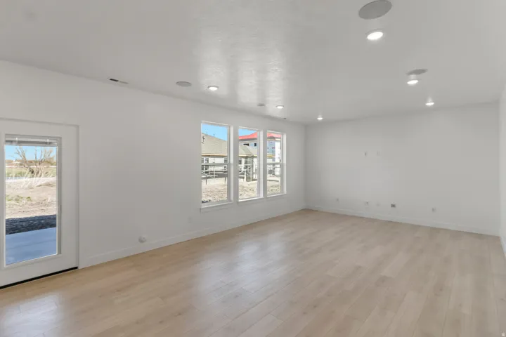 Recessed lighting, wood-finish flooring, white walls, multiple windows, and a glass-paneled door