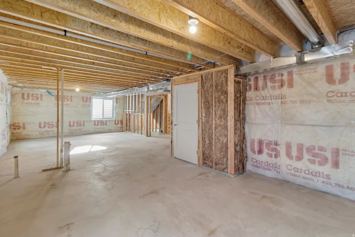 Unfinished lower level with exposed ceiling joists, concrete flooring, and an egress window with white louvered blinds
