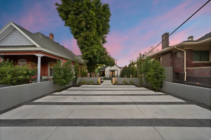 Concrete driveway with dark aggregate strips and retaining walls, leading to the property entrance