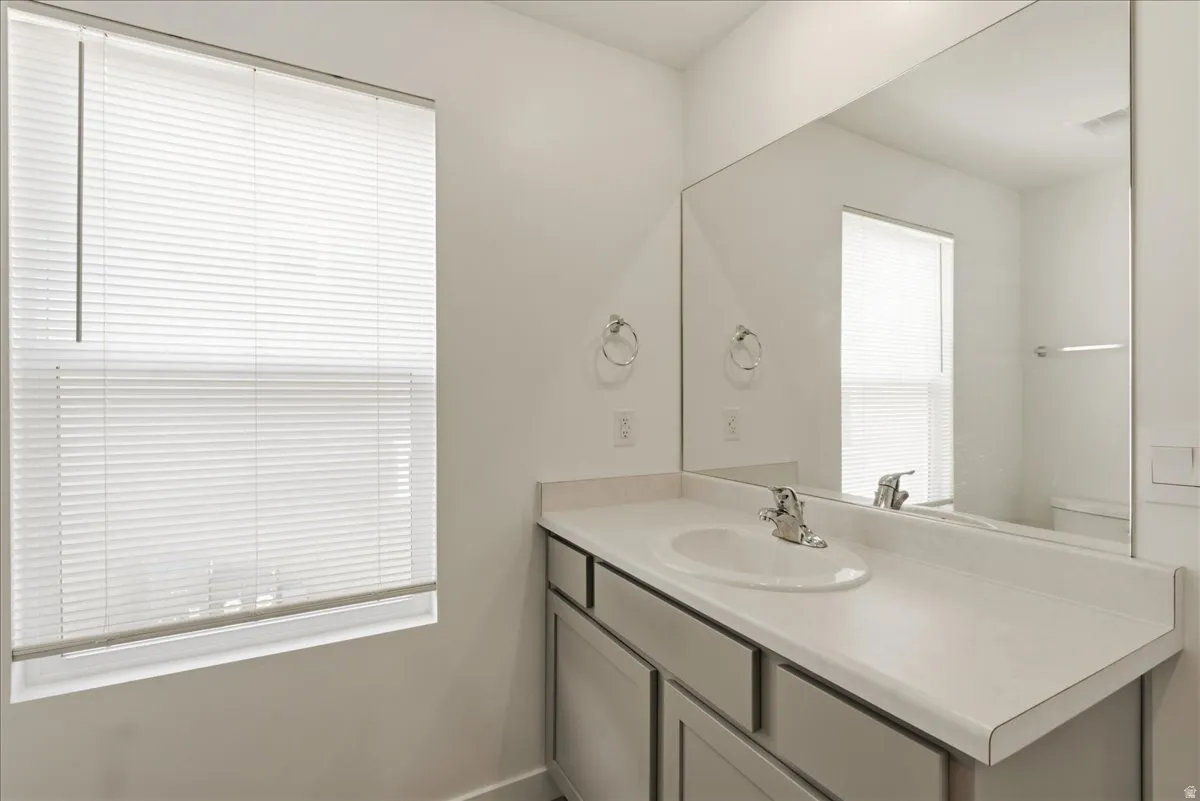 Vanity with an integrated sink, polished chrome faucet, gray cabinetry, and a large wall-mounted mirror