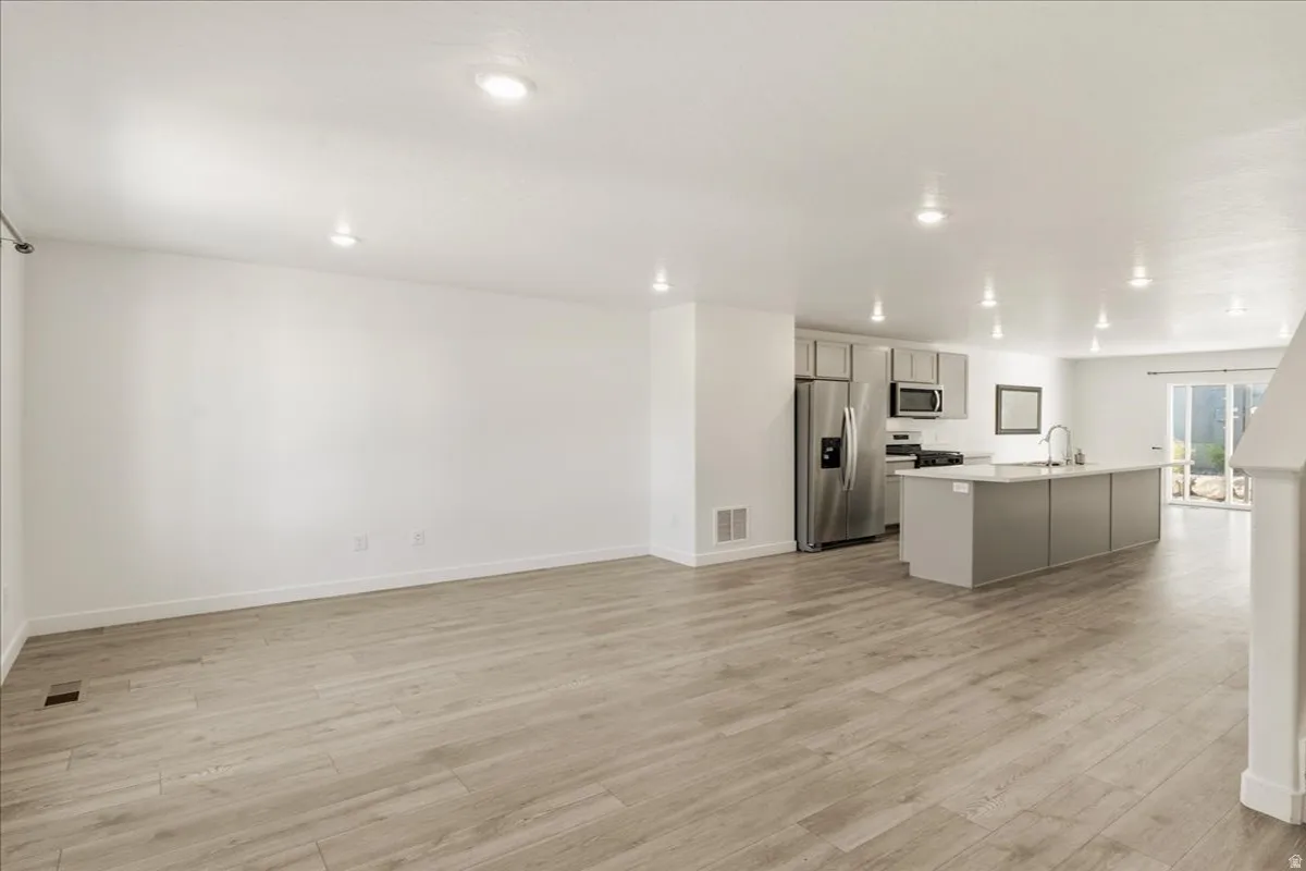 Open-concept living space with wood-finish flooring, recessed lighting, and a modern kitchen