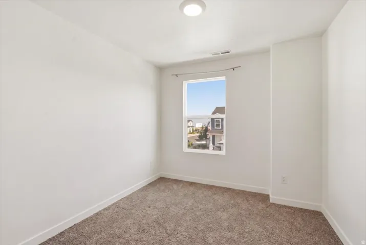 Neutral wall finishes, contemporary flush-mount ceiling light, window with white trim, and soft brown carpeting