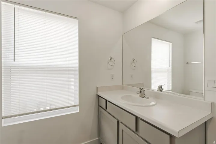 Vanity with an integrated sink, polished chrome faucet, gray cabinetry, and a large wall-mounted mirror