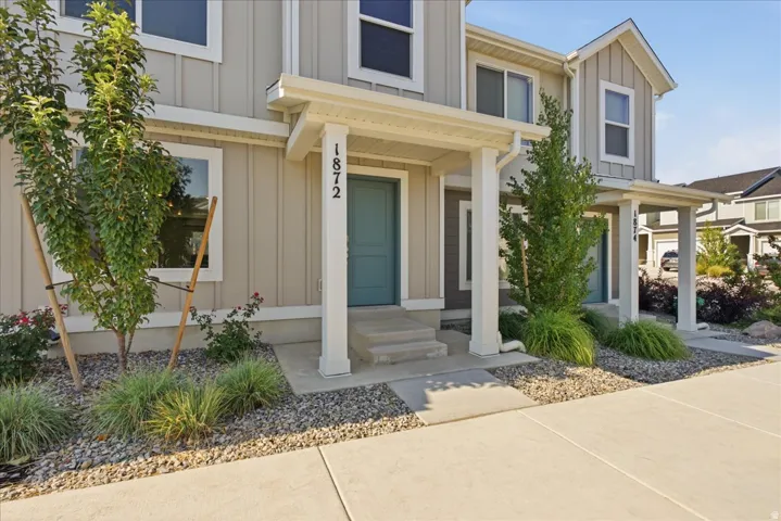 Vertical siding exterior featuring a covered entry, concrete steps, and established landscaping with decorative rock