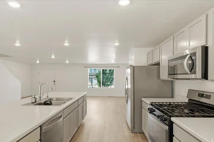 Kitchen featuring stainless steel appliances, light-toned cabinetry, a spacious island with an integrated sink, and recessed lighting