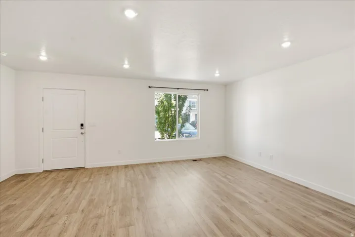 Recessed ceiling lighting, light wood-finish flooring, and white walls