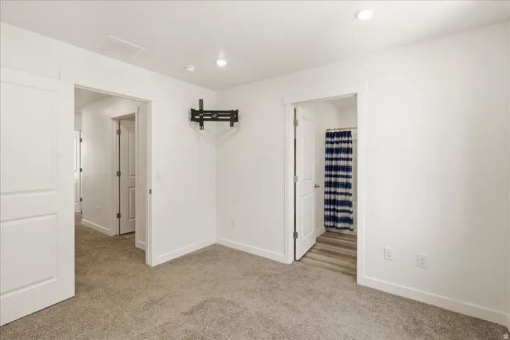 Wall-mounted television bracket, recessed ceiling lighting, and light gray carpeting