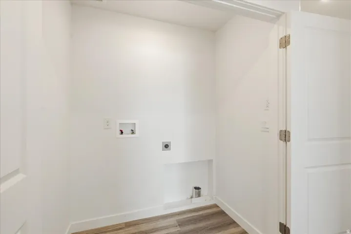 Dedicated laundry area with hookups for washer and dryer, wood-finish flooring, and a panel door