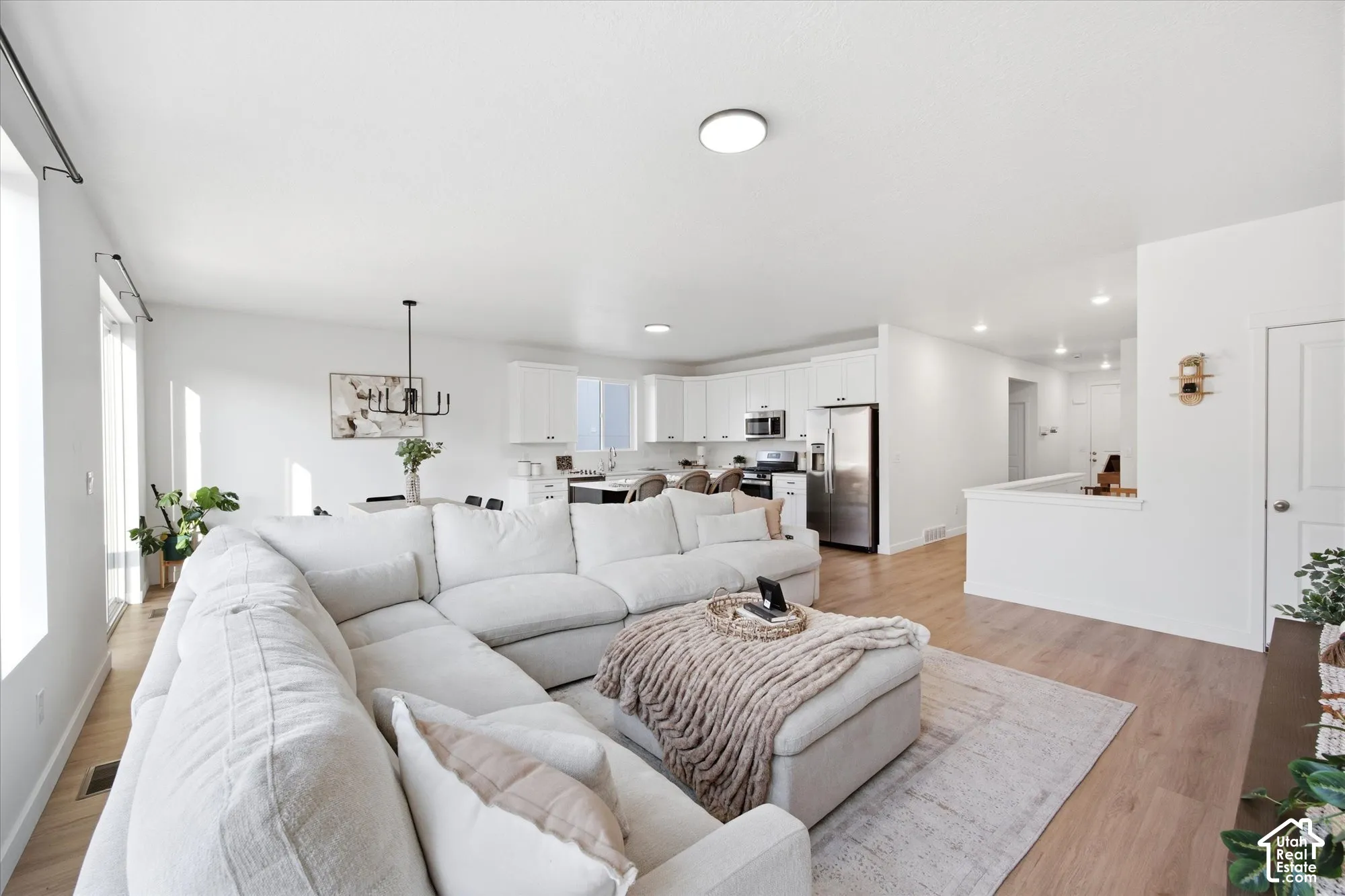 Open-concept living area featuring light wood-finish flooring, white walls, and recessed lighting