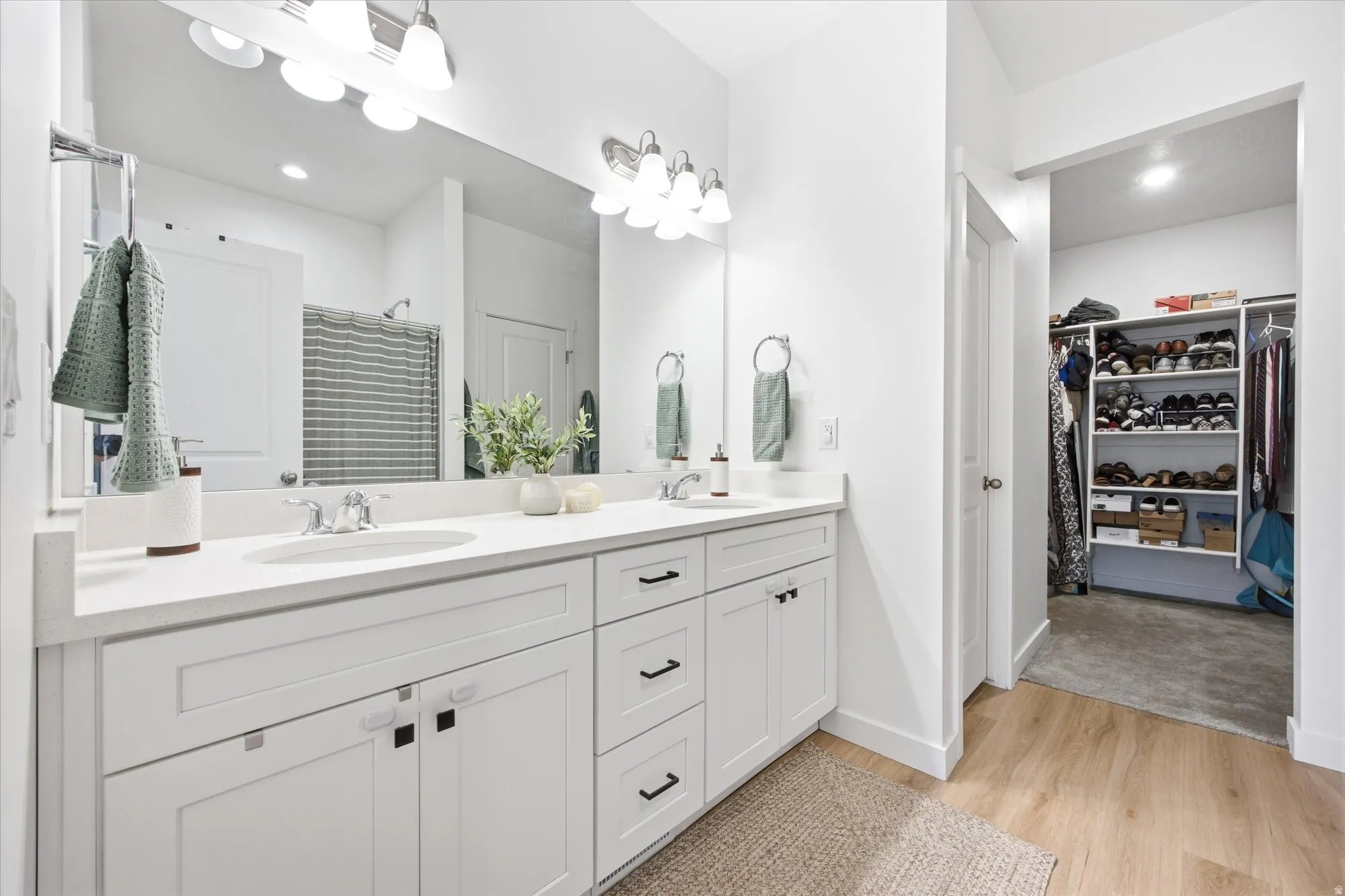 Dual vanity with white cabinetry, polished chrome fixtures, and a large mirror