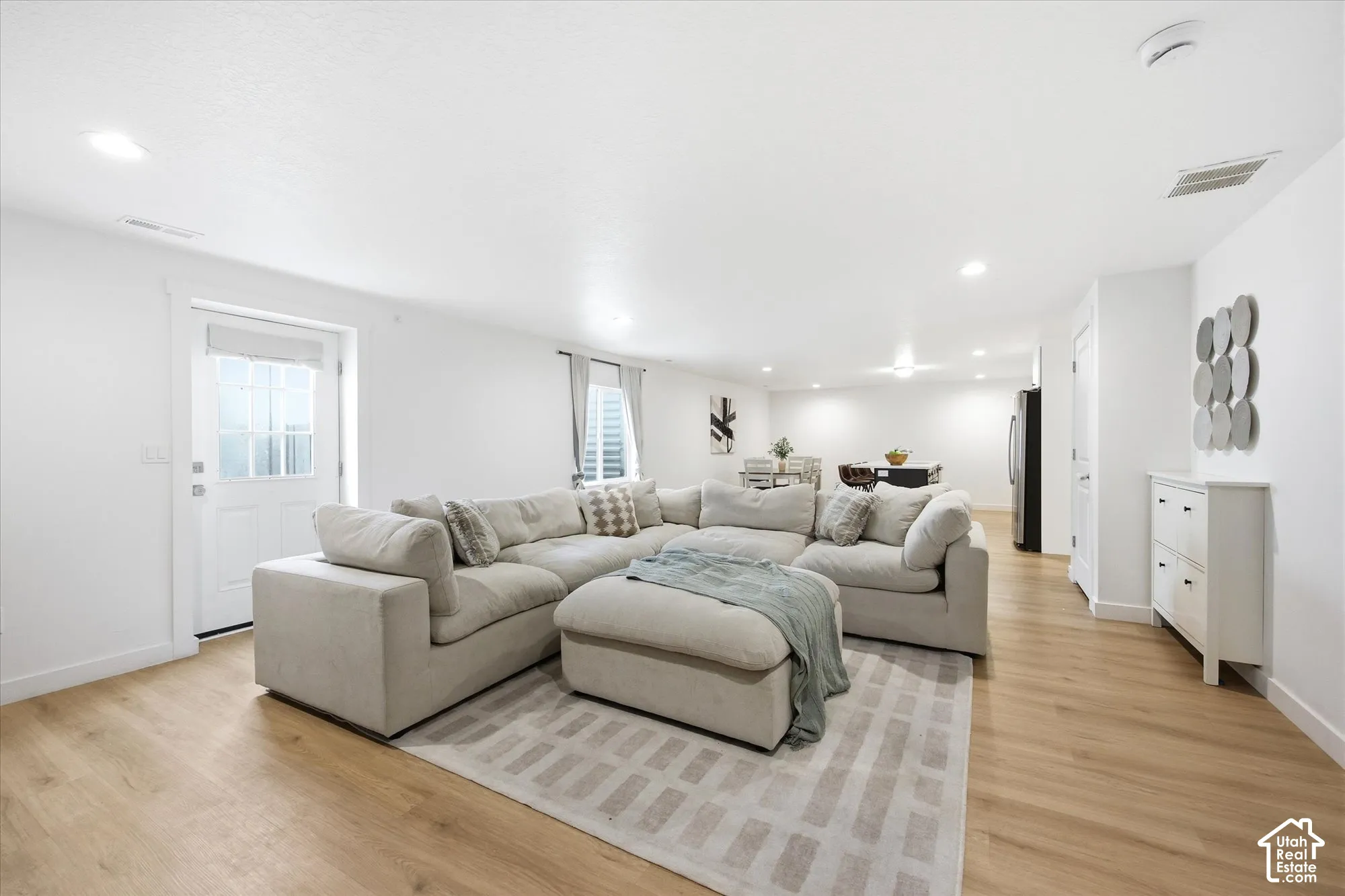 Recessed lighting illuminates the open-concept living space with wood-finish flooring