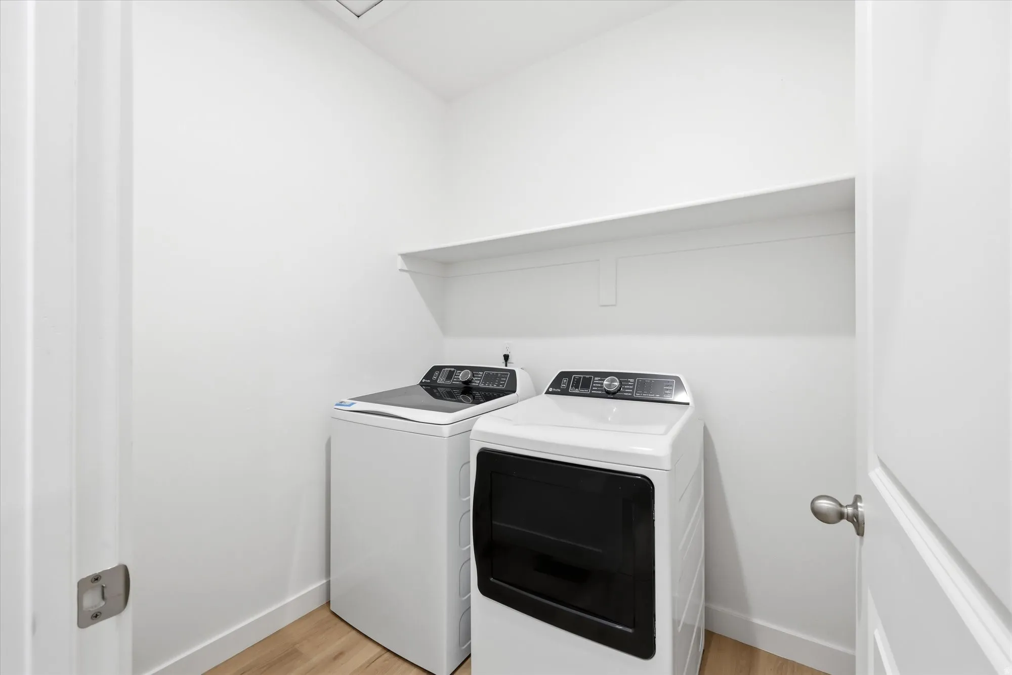 Laundry area featuring a built-in shelf, light wood-finish flooring, and white walls