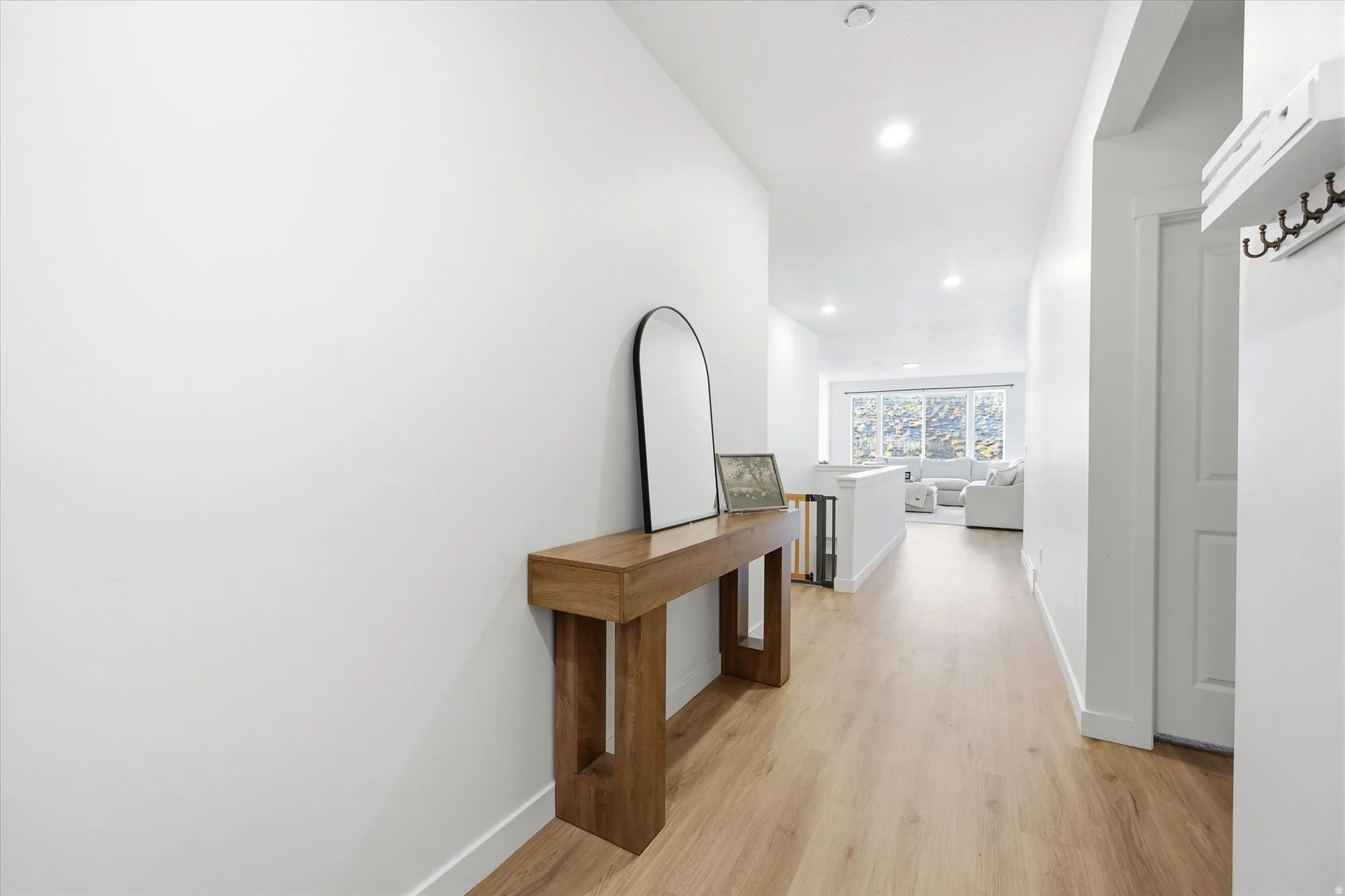 Recessed lighting illuminates the wood-finish flooring and white walls