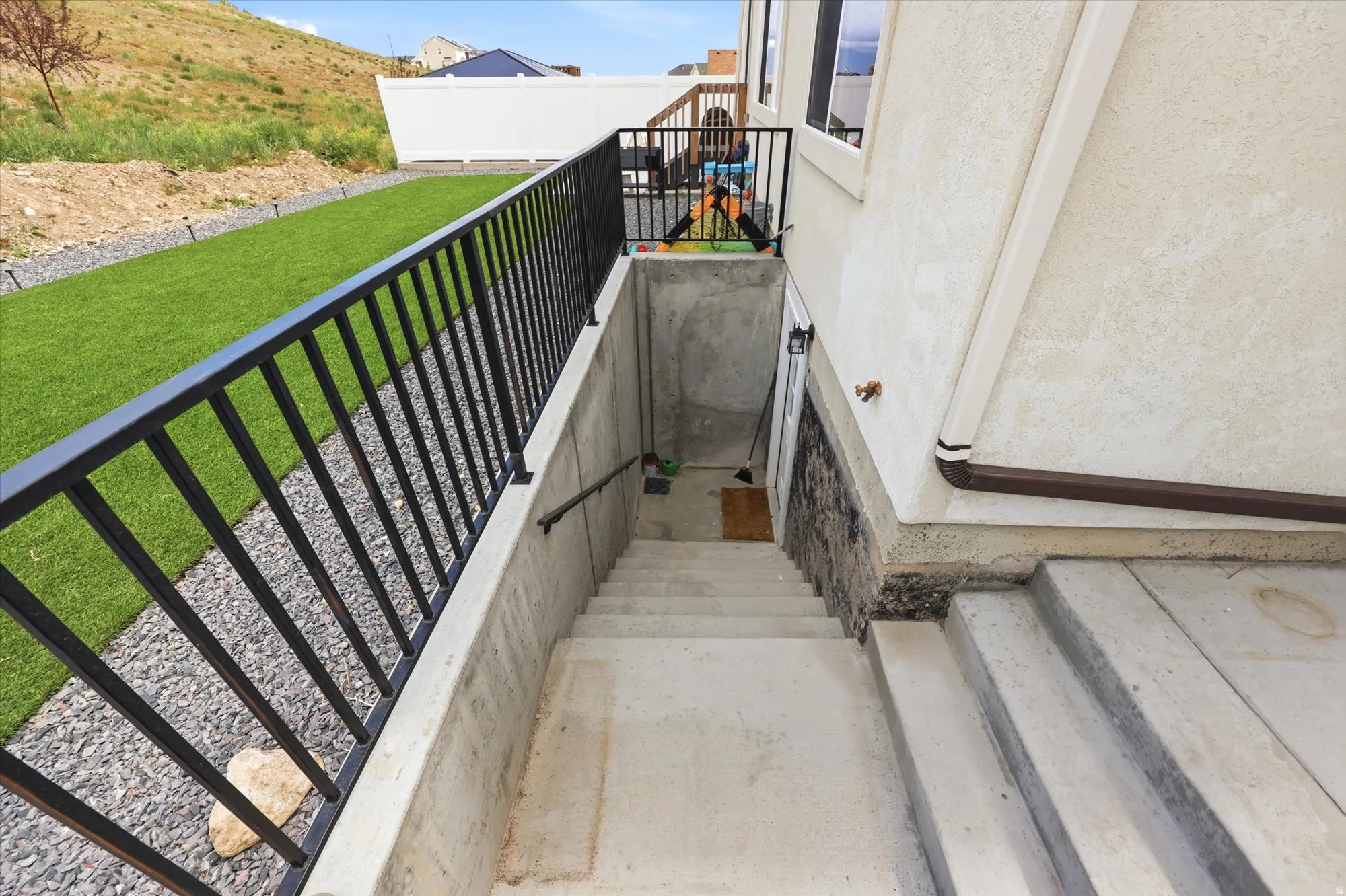 Concrete exterior stairs with metal railings, leading to a lower level entrance