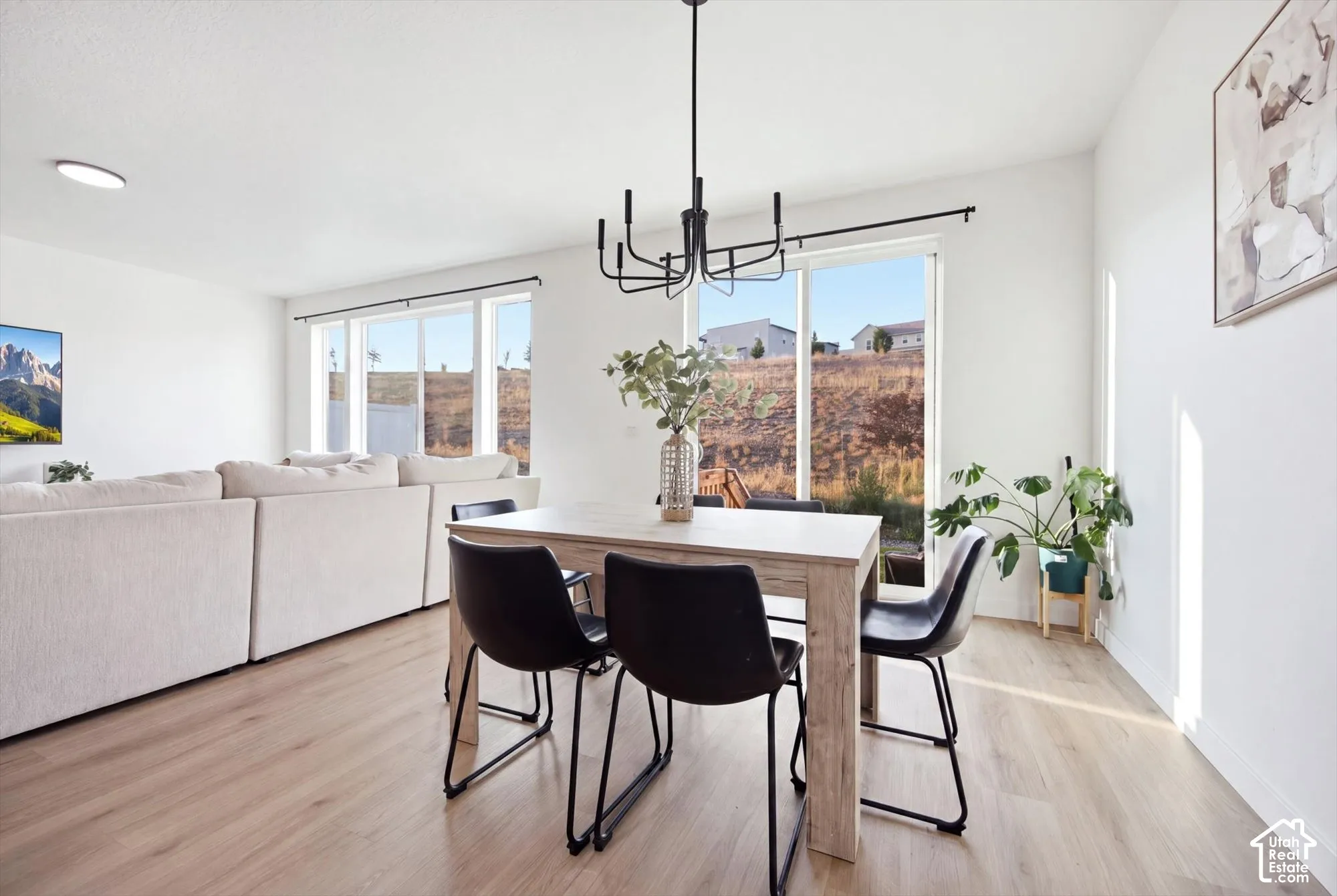Wood-finish flooring throughout, multiple large windows, and a contemporary black chandelier